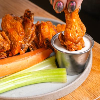 Chicken wing being dipped into a sauce on a plate.
