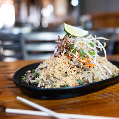 Thai Pearl Pad Thai on a wooden table with chopsticks.