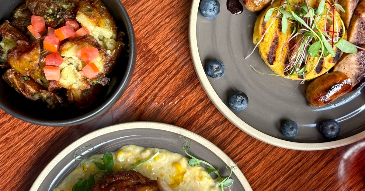 Brunch spread featuring smashed potatoes, grilled corn cakes, sausages, and blueberries