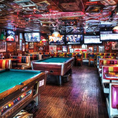 Cozy bar with colorful booths, two pool tables, multiple TVs, and vintage decor