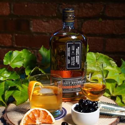 Bourbon whiskey alongside a cocktail, arranged on a wooden surface with garnsihes.
