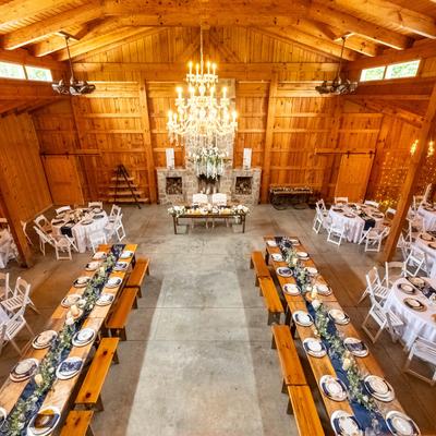 Rustic barn interior with an elegant wedding setup and chandeliers, top view.