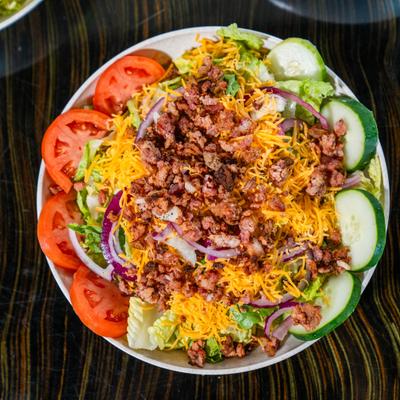 Salad with lettuce, tomatoes, onions, cheddar, bacon, and croutons.