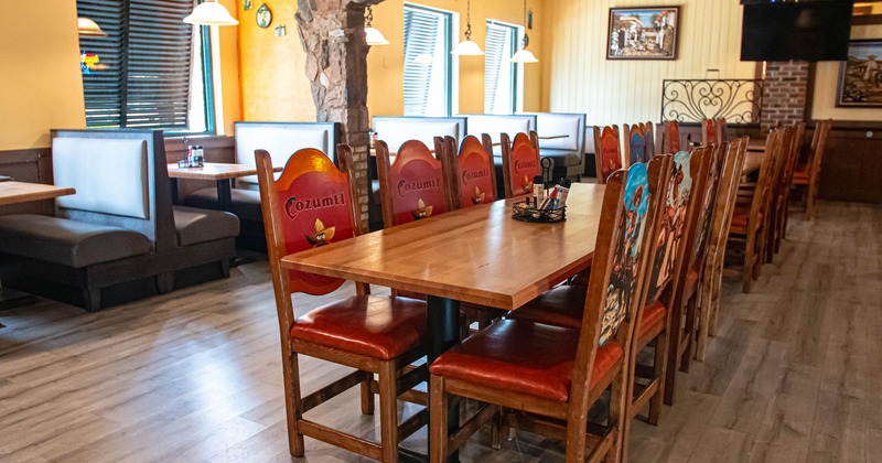 Interior of a Mexican-themed restaurant with wooden tables, chairs and booths.