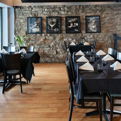 Interior, tables and chairs ready for guests, stone wall, large window area, framed pictures.