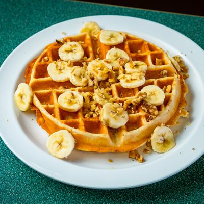 Waffle topped with banana slices and nuts.