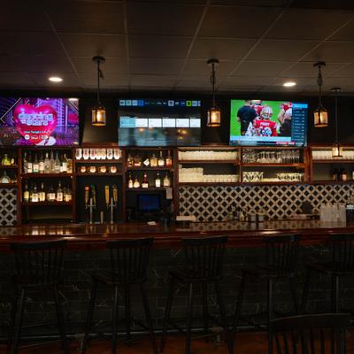 Bar area with shelves of liquor, beer taps, and TVs.