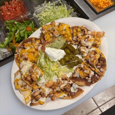Plate of loaded nachos topped with melted cheese, beans, guacamole and sour cream.