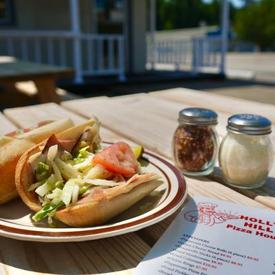 Cold-cut sandwich with lettuce and tomato, served with condiments.