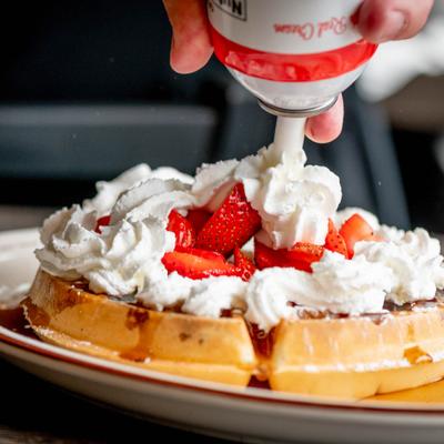 Waffle topped with strawberries and whipped cream.