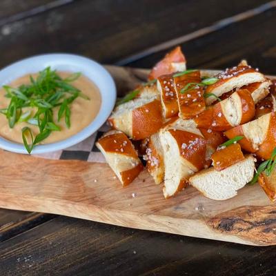 Bourbon Beer Cheese with pretzel bread served on a wooden board.