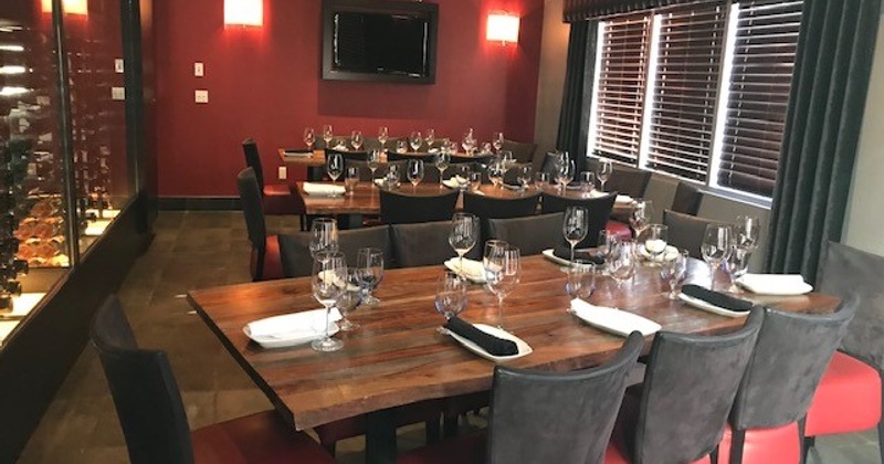 Elegant dining room with a polished wooden table, neatly set with wine glasses and napkins