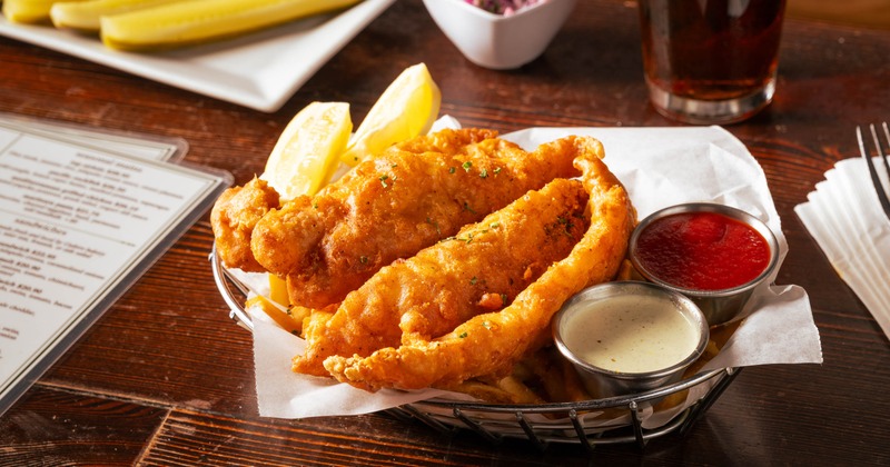 Fried fish served with fries, lemon wedges and dipping sauces