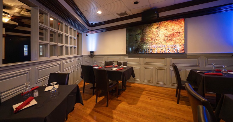 Restaurant dining area with tables set with black tablecloths and red napkins