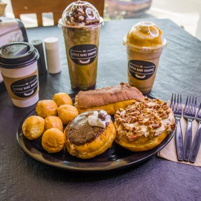 Spread of assorted donuts, a pastry, and several iced and hot coffee drinks.