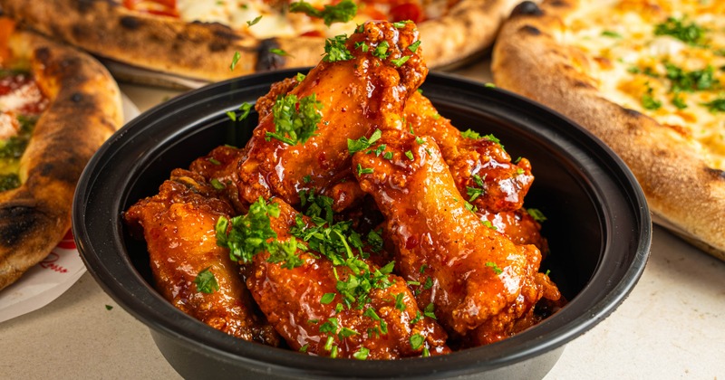 Glazed chicken wings with herbs in a takeout container