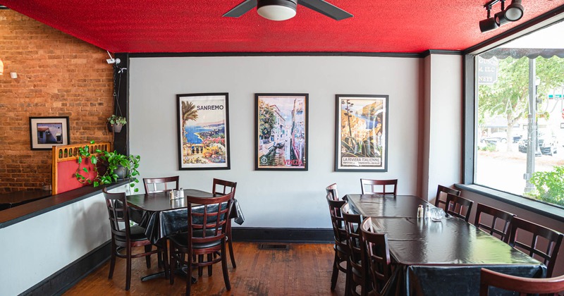 Interior, dining tables by a window, wall decorated with framed pictures