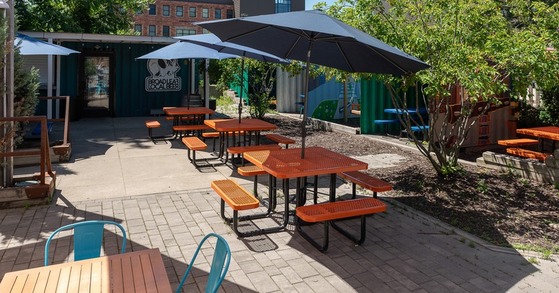Cozy outdoor seating area with conjoining tables and benches and black parasols