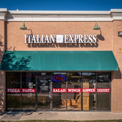 Storefront with signage, brick facade, and a green awning.