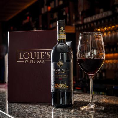 Red wine bottle beside a filled wine glass.