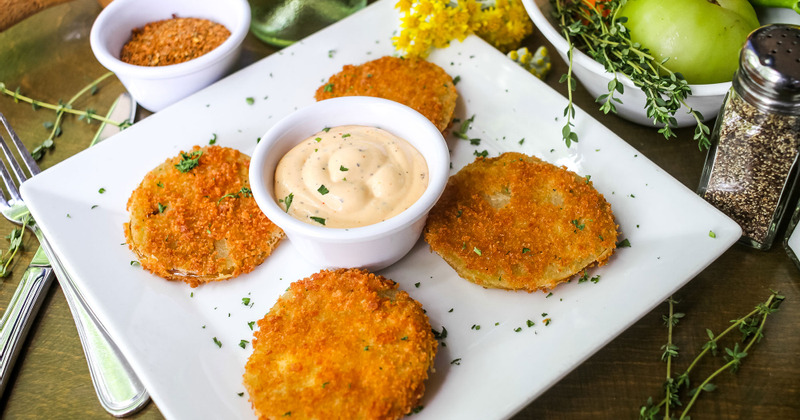 Four Fried Green Tomatoes on Plate with Spicy Cajun Dipping Sauce in Center