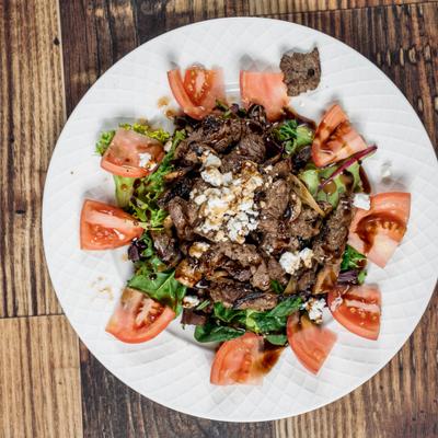 Filet Mignon Salad with greens, tomato, crumbled cheese and a balsamic glaze.