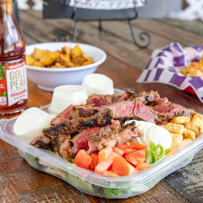 Ribeye Steak Salad served alongside an Iced Tea and other food items.