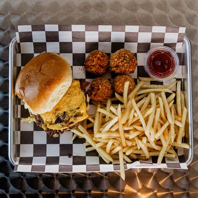 Cheeseburger with fries, fried rice balls, and ketchup on a tray.
