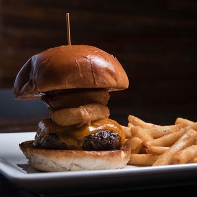 Cowboy Burger with melted cheese, onion rings, BBQ sauce and a side of fries.