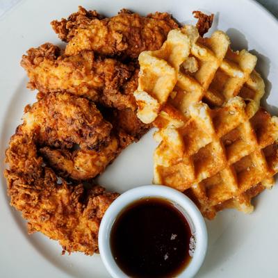 Chicken and waffles served with syrup.