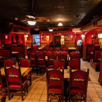 Vibrant red decor, wooden chairs, tiled floor, warm lighting, and decorative wall art.