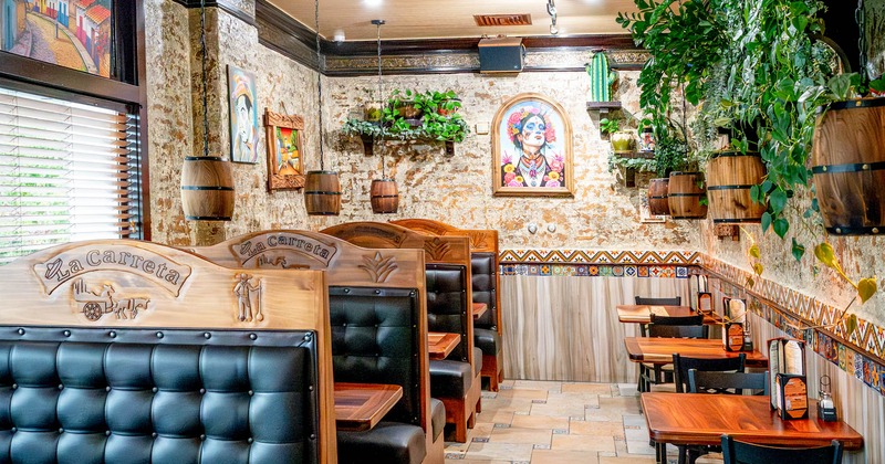 Restaurant interior with wooden booths, colorful art, and hanging plants
