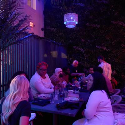 People dining outdoors under purple lighting.