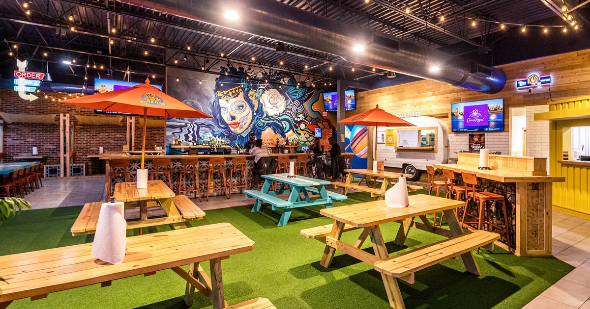 Interior, seating area, wooden tables with parasols and benches, bar in the back