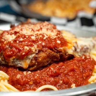 Chicken Parmesan served over a bed of spaghetti pasta.