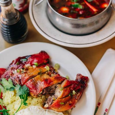 Roasted chicken, on a bed of rice, with a sunny side up egg, tomato, and cucumber.