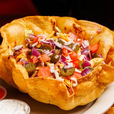 Taco Salad served in a deep-fried flour tortilla bowl with sides of sour creme and salsa.