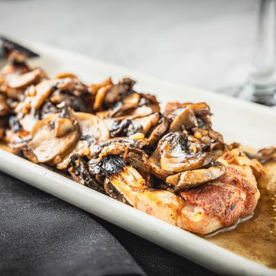 Shrimp wrapped in bacon, topped with mushrooms, close-up.