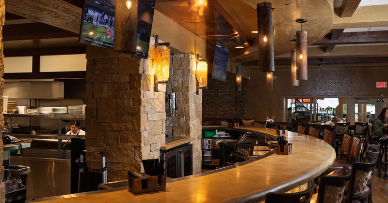 Interior, curved marble top bar with stylish wooden stools, kitchen in the back