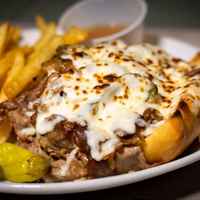 Italian beef sandwich with melted mozzarella cheese, fries, and pepperoncini.
