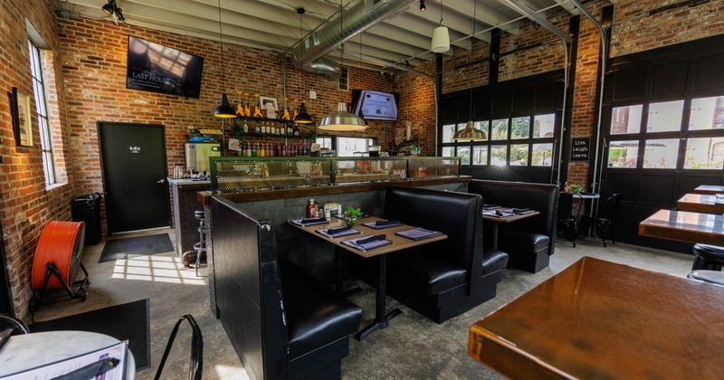 Interior seating area with a central bar, black leather booths, and wooden tables