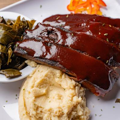 Pork Rib Dinner with sides of mashed potatoes and collard greens.