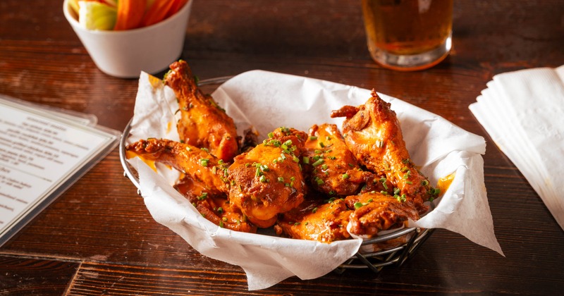 Basket of Buffalo wings served alongside celery and carrot sticks