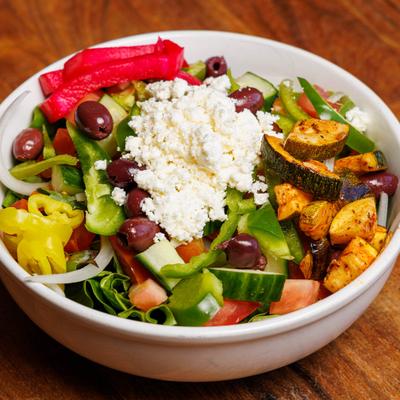 Greek House Salad bowl on a wooden table.