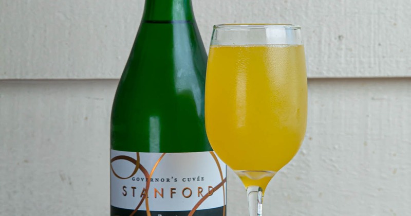 A served mimosa drink with a bottle of champagne