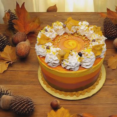 A colorful autumn-themed cake surrouneded by acorns and pinecones on a table.