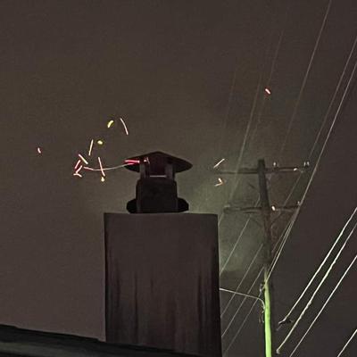 Smoke stack at night while pit-master cooks shoulders.