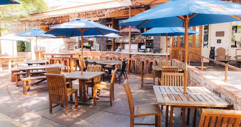 Exterior, tables and chairs with parasols, red brick wall, bar in the back, lantern decoration