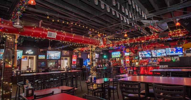 Interior of a bar showcasing red tables and chairs for seating