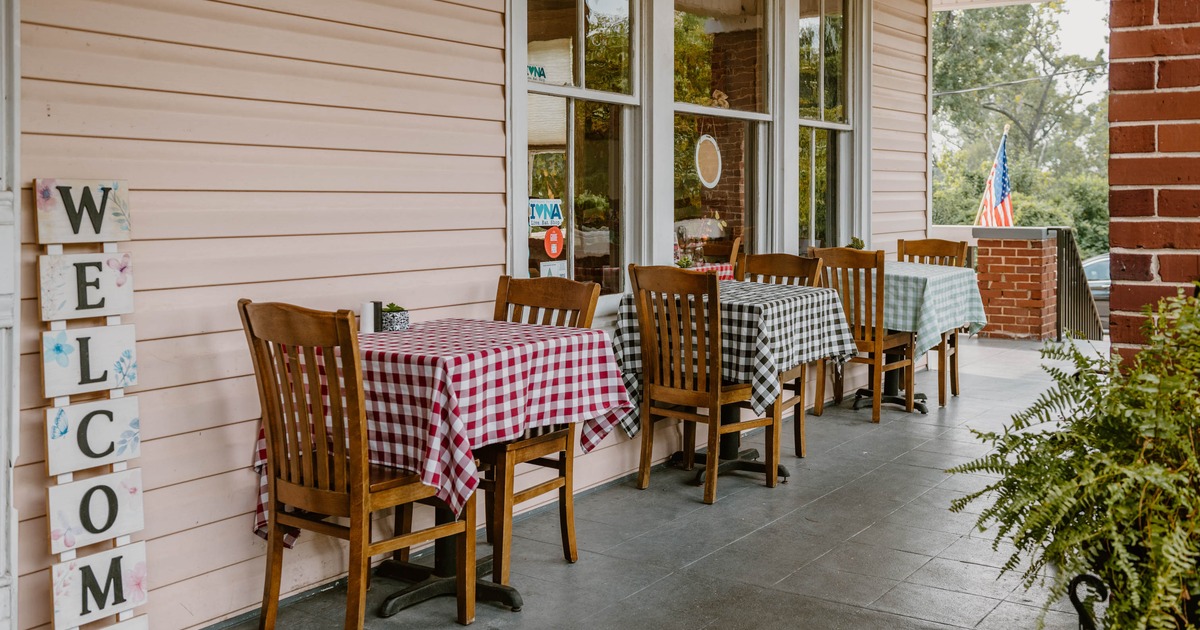 Outdoor porch with tables covered in checkered tablecloths and a 